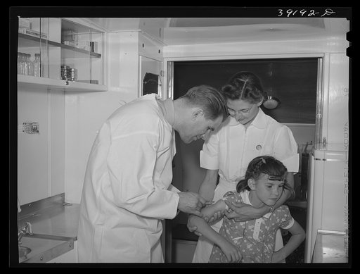 Doctor and nurse with little girl in trailer-clinic at the FSA (Farm Security Administration) migratory labor camp mobile unit. Wilder, Idaho