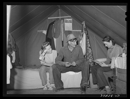 Farm worker and his two daughters in the tent in which they live at the FSA (Farm Security Administration) migratory labor camp mobile unit. Wilder, Idaho