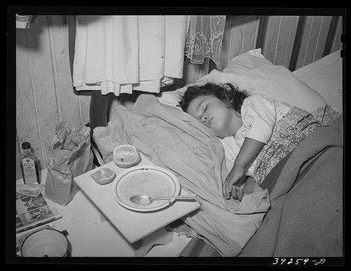 Sick child in bedroom of house in the Mexican section. Seven children and two adults sleep in two small rooms and in two beds and on the floor in this house. They pay eleven dollars per month for three rooms, no bath, outside toilet