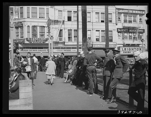 Sailors lined up against chain-rail in square in midtown. San Diego, California