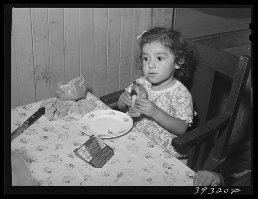 Little Mexican girl eating enchilada for lunch. San Diego, California