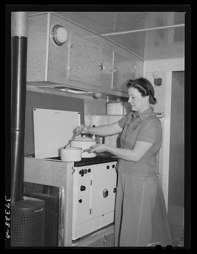 Wife of aircraft worker at the stove in her trailer home at the FSA (Farm Security Administration) camp for defense workers. San Diego, California