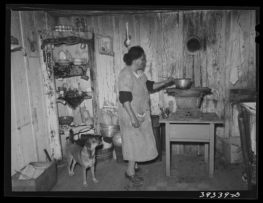 Mexican woman in her house for which she pays six dollars per month. It has no electricity, no bath, no gas. An outside toilet is used by six families. San Diego, California