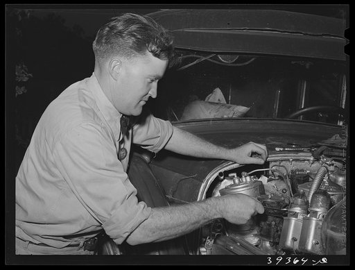 Consolidated Aircrafts workman working on his self-assembled automobile. This is a diesel motor in this car. San Diego, California