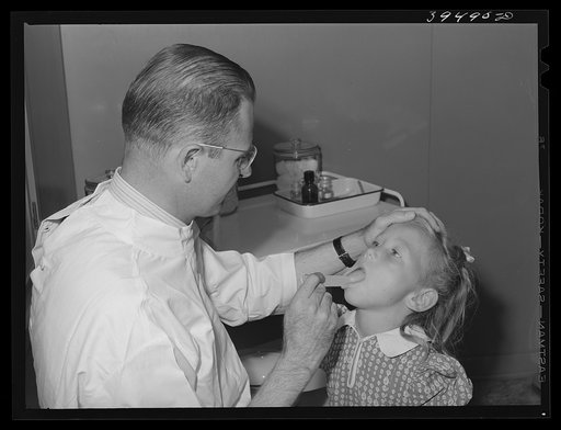 Doctor examines daughter of farm worker living at the FSA (Farm Security Administration) labor camp. Caldwell, Idaho