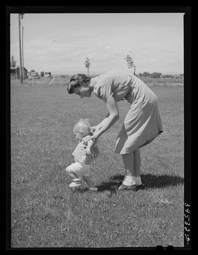 Farm worker's wife teaches her baby girl to walk at the FSA (Farm Security Administration) labor camp. Caldwell, Idaho