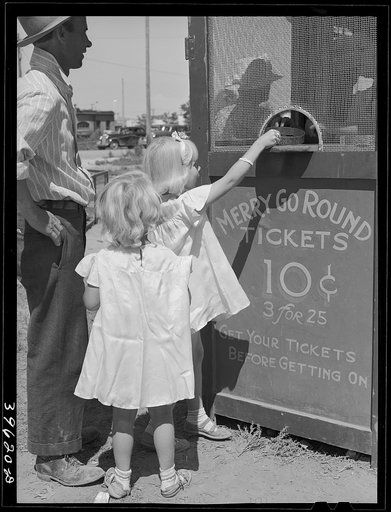 Little girls getting tickets for the merry-go-round at the carnival on the Fourth of July. Vale, Oregon