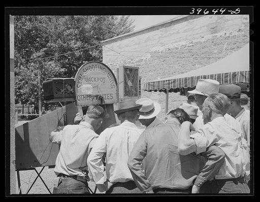 Untitled photo, possibly related to: Men gathered around one of the carnival attractions which was in Vale, Oregon, for the Fourth of July celebration