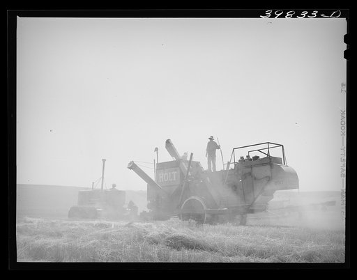 Tractor-drawn combine in wheat field on Eureka Flats. Walla Walla County, Washington