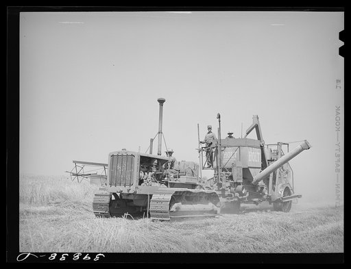 Caterpillar tractor and combine in wheat field on Eureka Flats. Walla Walla County, Washington
