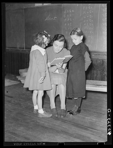 Lancaster County, Pennsylvania. Martha Royer teaching two first graders in her one-room schoolhouse. There are fourteen pupils in the school and the grades run from first to second year high school. The little girl on the right comes from an Amish family