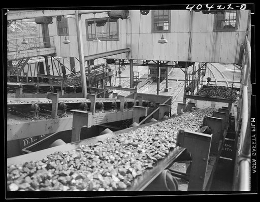 Untitled photo, possibly related to: Gilberton, Pennsylvania. A company inspector examining coal on a car loading belt at the Saint Nicholas breaker, one of the two largest coal breakers in the world