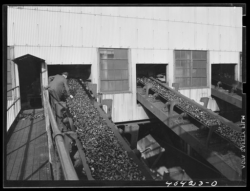 Gilberton, Pennsylvania. A company inspector examining coal on a car loading belt at the Saint Nicholas breaker, one of the two largest coal breakers in the world