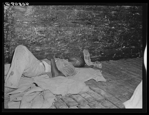 Migratory agricultural worker asleep in boxcar. Camden, North Carolina