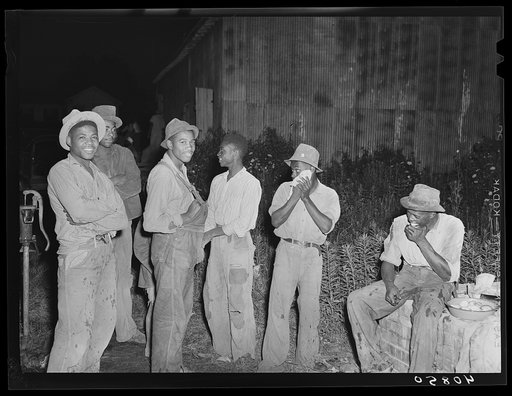 Group of migratory agricultural workers at grading station at Belcross, North Carolina, stop to wash and have their supper