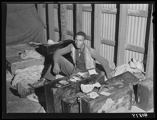 In the attic of the grading station at Belcross, North Carolina, are living quarters for some of the migratory agricultural workers. The luggage separates one "room" from another