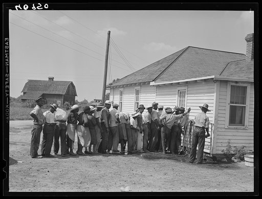 Migratory agricultural workers getting in line to be paid for picking beans. They get seven cents a hundred pounds