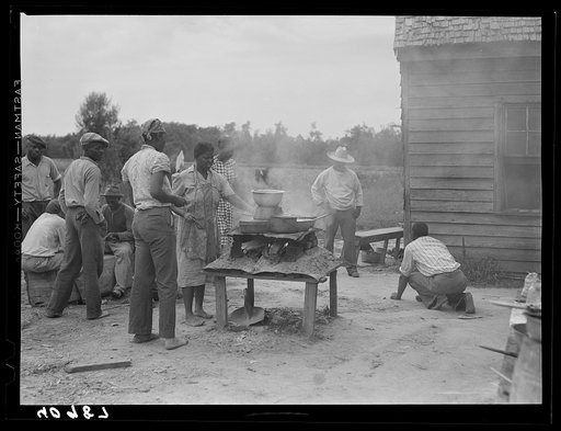 Over this stove, cooking is done for the thirty five migrants that stay in this house in the background. Near Old Trap, North Carolina