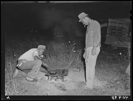 Mirgratory agricultural workers from the grading station at Belcross, North Carolina, cook their own supper of potatoes and salt pork