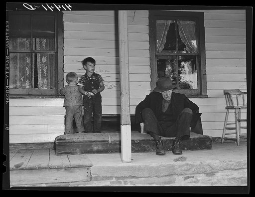 On the porch of Mr. Shoemaker's house. Blind old man and Mr. Shoemaker's children. They are farmers in the submarginal farm area of Rumsey Hill, near Erin, New York