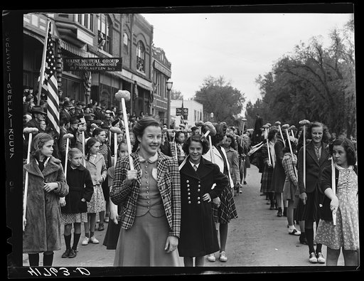 Schoolgirls carrying Aroostook potatoes on sticks a part of the parade on the day of the barrel rolling contest in Presque Isle, Maine