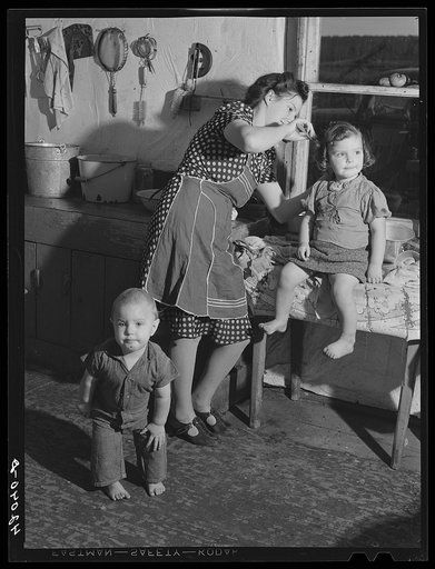 Young French-Canadian wife of poor potato farmer near St. Agatha, Maine. She is eighteen years old. Fixing up her children to "have their picture taken"