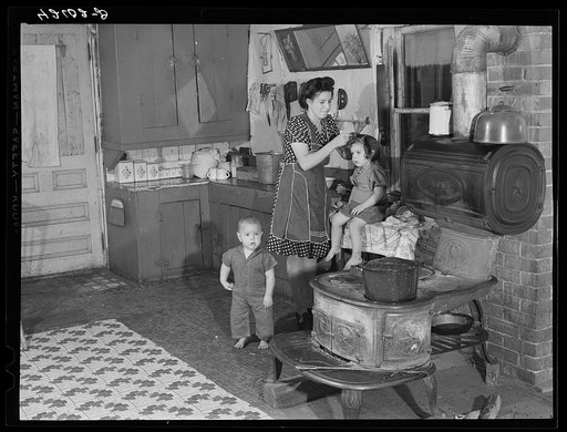 Young French-Canadian wife of poor potato farmer near Van Buren [i.e. St. Agatha], Maine. She is eighteen years old. Fixing up her children to "have their picture taken"