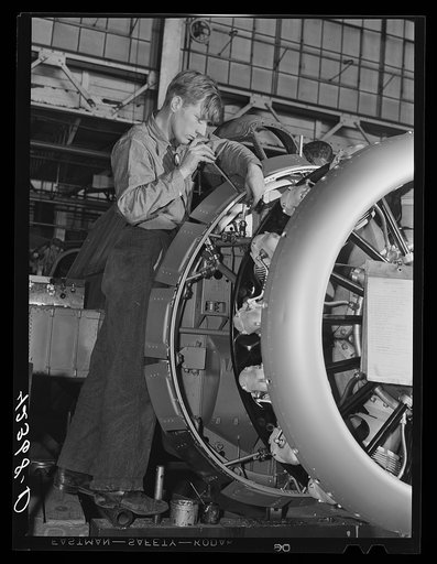 Working on the intricate job of fitting the engine to the fuselage of a plane at The Vought Sikorsky Aircraft Corporation. Stratford, Connecticut