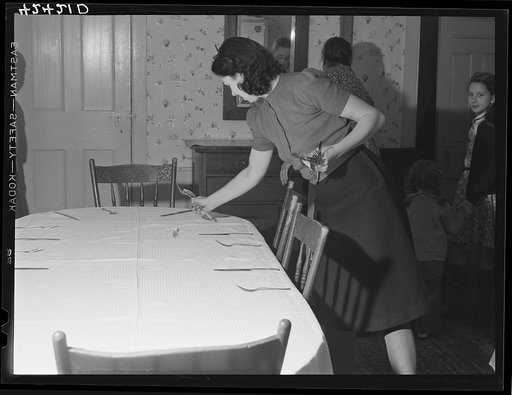 One of the daughters of Mr. T.L. Crouch setting the table for the family on Thanksgiving Day