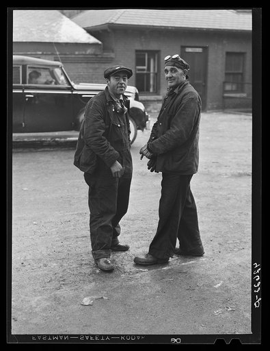 Two shipyard workers talking just outside the gates to the shipyard during lunch hour