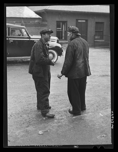 Untitled photo, possibly related to: Two shipyard workers talking just outside the gates to the shipyard during lunch hour