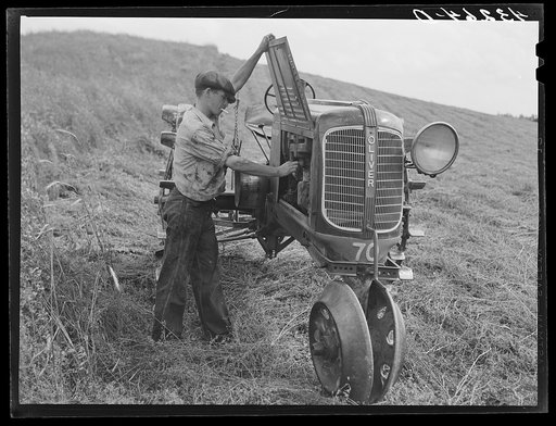 Making adjustments on tractor. Farm near Rockville, Maryland