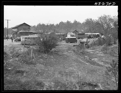 Untitled photo, possibly related to: Part of a trailer camp for migratory workers, employed at Fort Bragg, North Carolina. Trailer space is one dollar a week, and small bunk houses five dollars a week. One water spigot near the general store serves the whole camp until 6 p.m. On the left is an old t