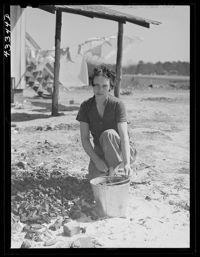 Woman who lives with her family in the upper part of tobacco barn, gathering coal. Husband works at Fort Bragg. Near Fayetteville, North Carolina