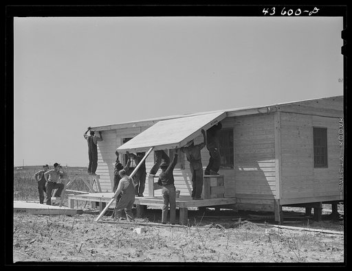 Building porch on prefabricated houses to be used to house some of the farmers that had to move out of Camp Croft area. Pacolet, South Carolina