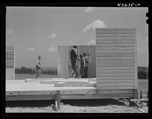 Bolting a section of a wall on one of the prefabricated houses built by the FSA (Farm Security Administration) for farmers moved out of the Camp Croft area. Near Pacolet, South Carolina
