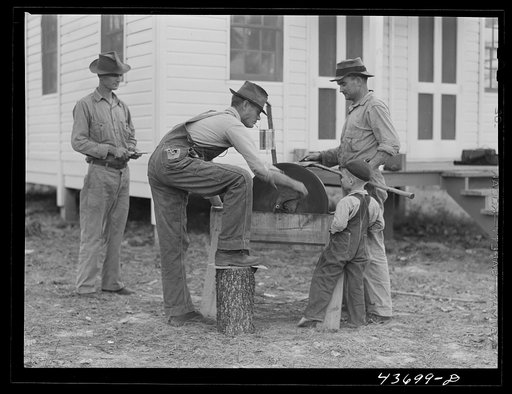 Untitled photo, possibly related to: Farmers at Hazlehurst Farms Inc., sharpening an ax preparatory to going out to clear land. Hazlehurst, Georgia