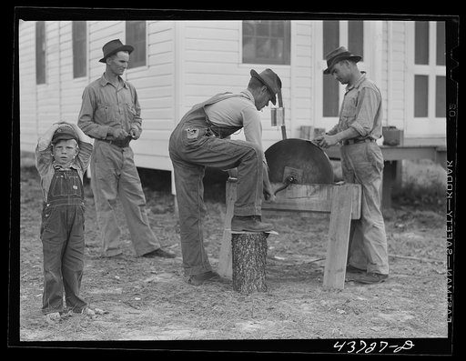Farmers at Hazlehurst Farms Inc., sharpening an ax preparatory to going out to clear land. Hazlehurst, Georgia