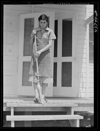 Mrs. Agnes Powell, sweeping porch of her prefabricated house at Hazlehurst Farms Inc., Hazlehurst, Georgia