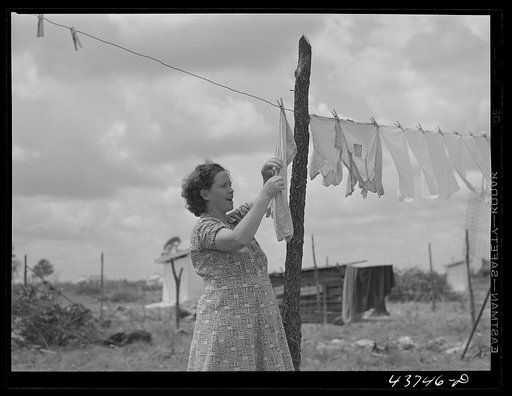 Mrs. Agnes Usher hanging clothes at her new prefabricated house at Hazlehurst Farms Inc. She had gone to Hinesville with her husband from Baxley, Georgia to work at Camp Stewart. When his work was over they moved to Hazlehurst Farms. Hazelhurst, Georgia.