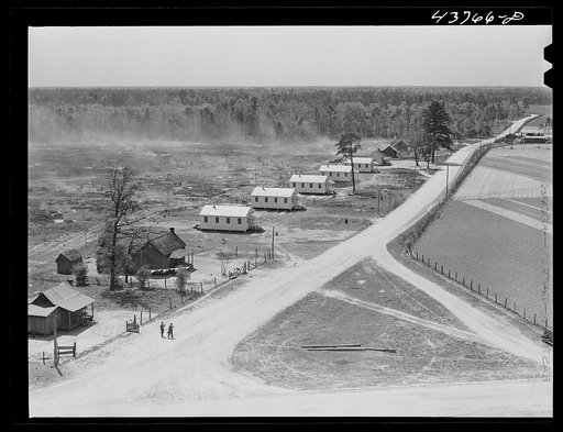 View of the prefabricated houses at Hazlehurst Farms showing the burning of brush in background, part of the land clearing program. Hazlehurst, Georgia