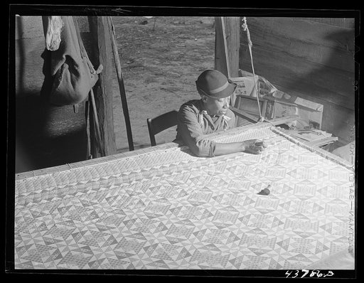 Untitled photo, related to: A woman who has not yet found a place to move out of the Hinesville Army camp area working on a quilt in her smokehouse. Near Hinesville, Georgia