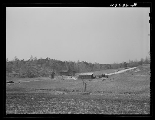 Untitled photo, possibly related to: This road is the Camp Croft boundary. The family who lived in the house at the left is moving into the barn on the right