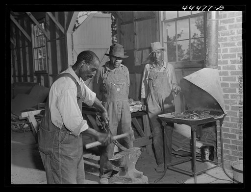 Negro farmers sharpening plow points in new vocational school. Greene County, Georgia