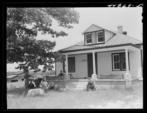 In the evacuated area of Caroline County, Army maneuvers are already being held. Soldiers take time out for lunch on the porch of an evacuated house. Virginia