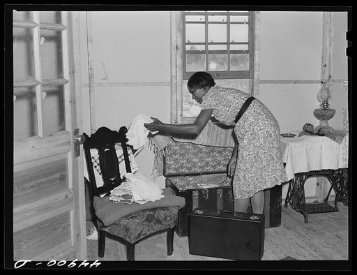 Unpacking their belongings in their new prefabricated house built by FSA (Farm Security Administration). Some farmers had to move out of the area being taken over by the Army in Caroline County, Milford, Virginia