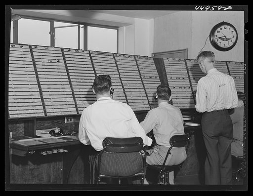 Untitled photo, possibly related to: In the airport control room with which incoming and outgoing airliners are in constant communication. Flight data is kept on the white slips of cardboard. A new electrical control board just completed on the opposite side of the room will replace this one Washing