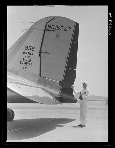 A ground crew assistant removing the block from the rudder preparatory to the plane's taking off. Municipal airport, Washington, D.C.
