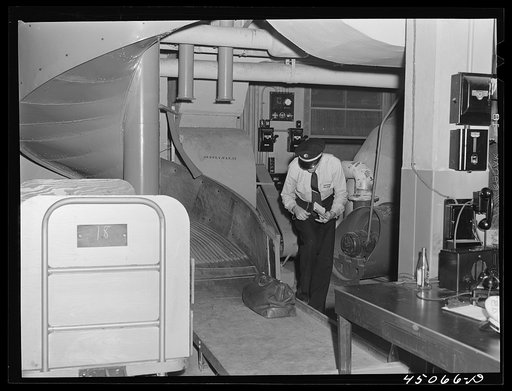 Checking the bags in the baggage department. The baggage comes down the chutes from the ticket counters directly above. Municipal airport, Washington, D.C.