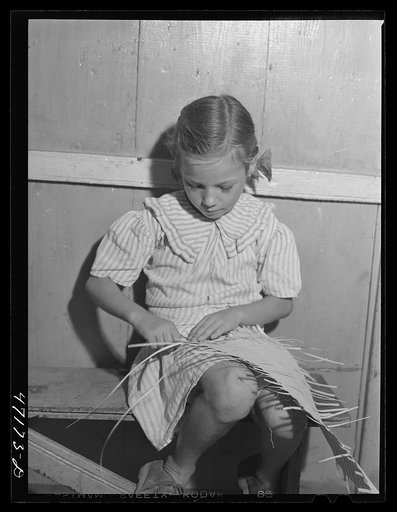 French village, a small settlement on Saint Thomas Island, Virgin Islands. Little girl weaving palm leaf mat to be sold at the handicrafts cooperative